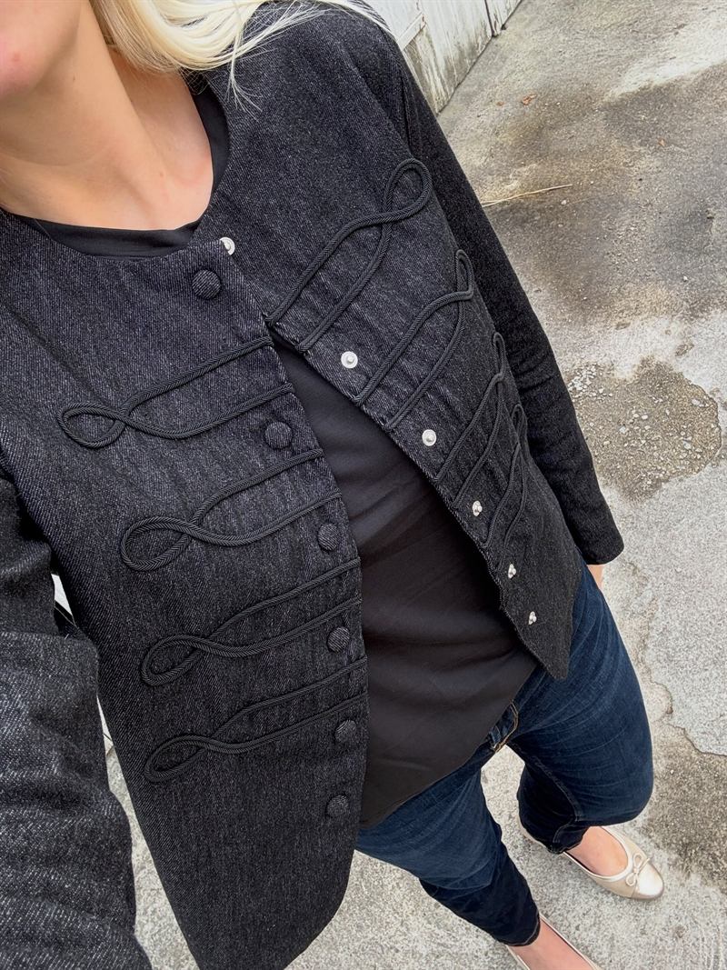 Mørk denimjakke med flettede snoredekorationer